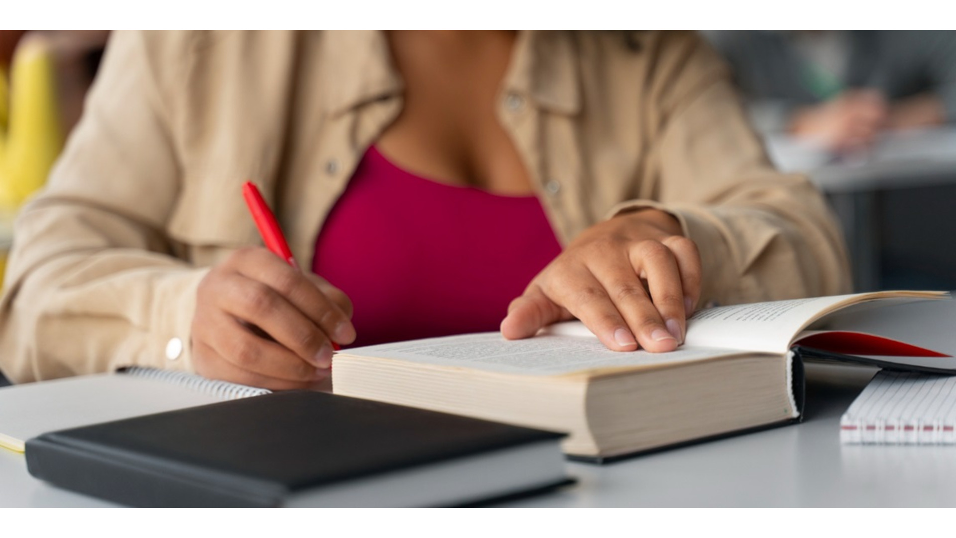 Pessoa fazendo anotações ao estudar com livros abertos