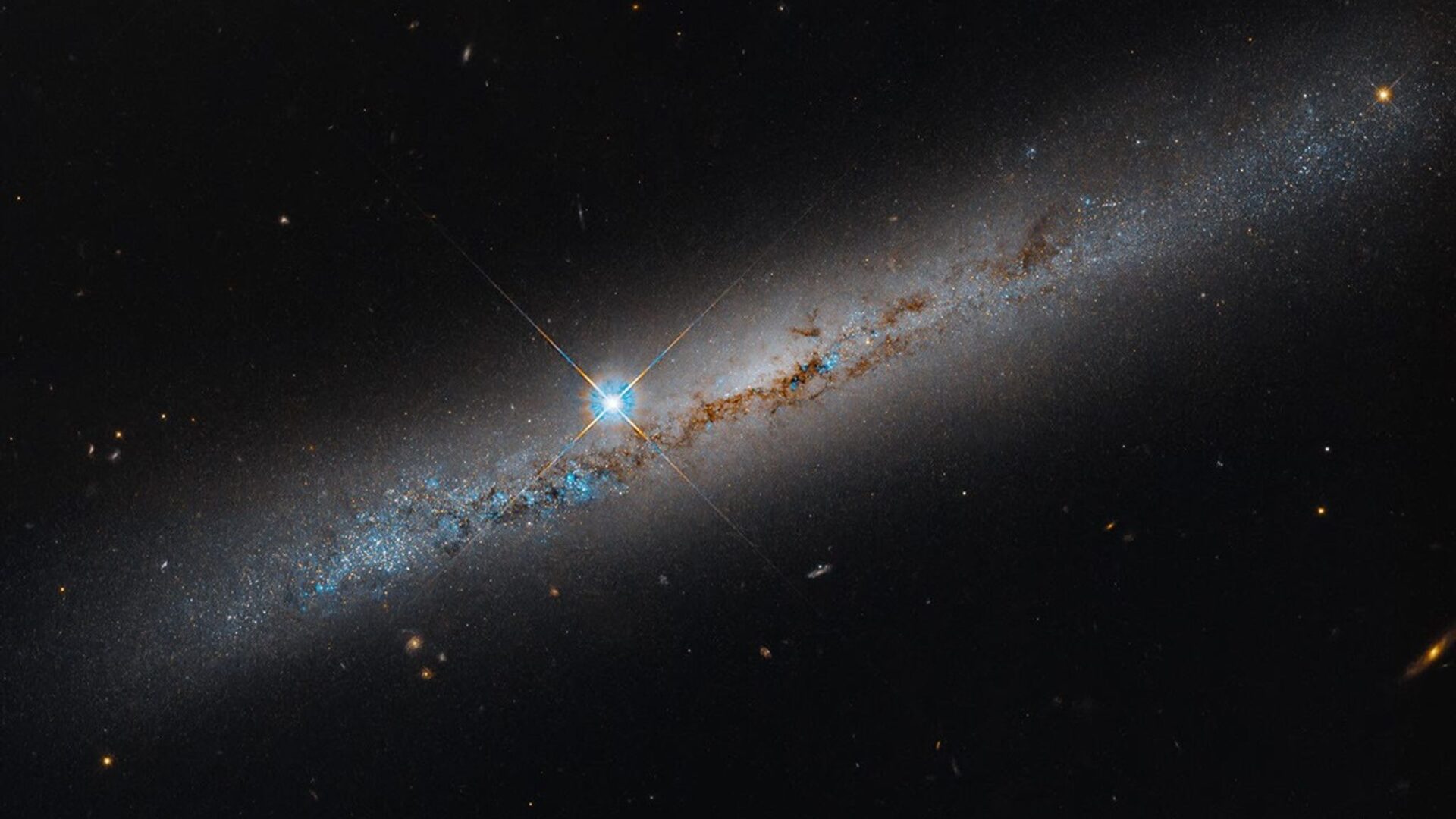 Imagem do Hubble mostra a galáxia NGC 1827 vista de lado, com faixas de poeira e estrelas.