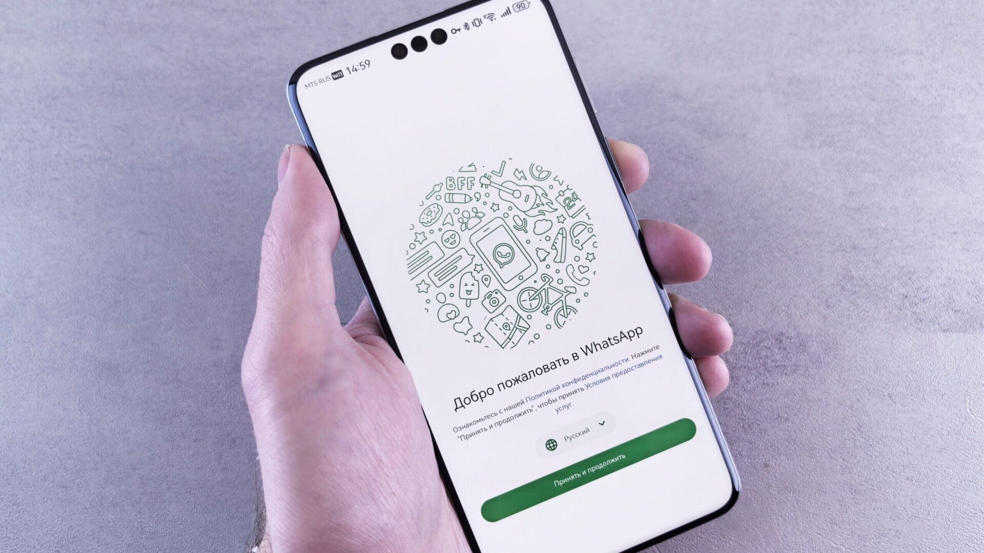 Mão segura smartphone com a tela de boas-vindas do WhatsApp.